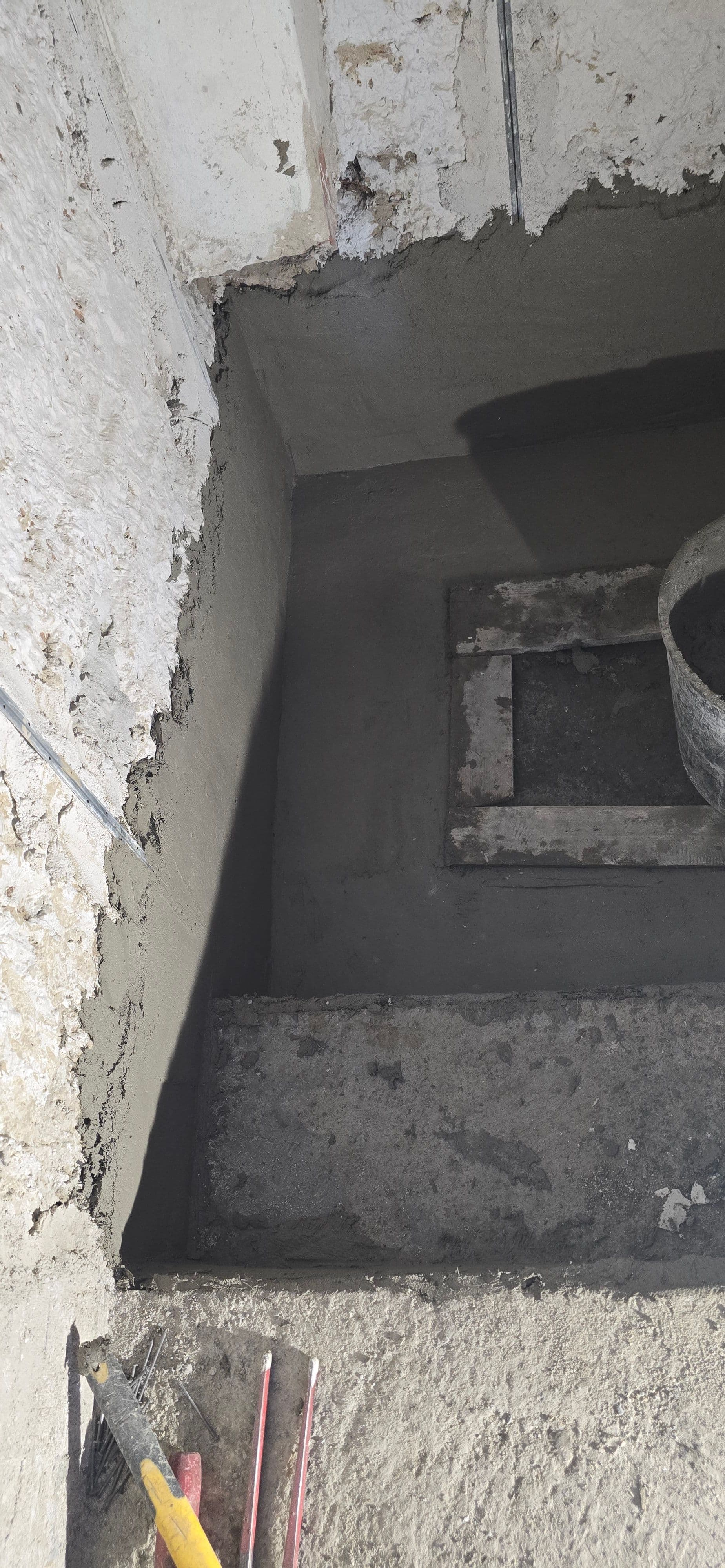 Dettaglio dell'applicazione di un sistema impermeabilizzante MAPEI su pareti e pavimento di una struttura sotto il livello del suolo. Si nota la stesura della malta osmotica grigia per il blocco delle venute d'acqua in controspinta.